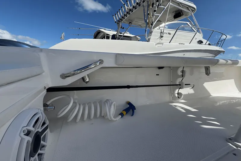Slide: The Image of 2021 Everglades 243 CC boat deck with fishing rod holders and coiled hose. - 26