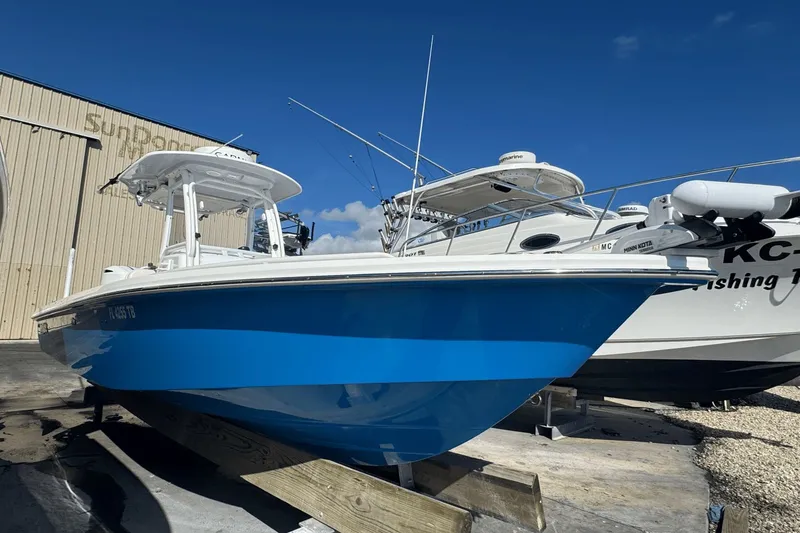 Slide: The Image of 2021 Everglades 243 CC boat in vibrant blue, docked beside another vessel. - 3