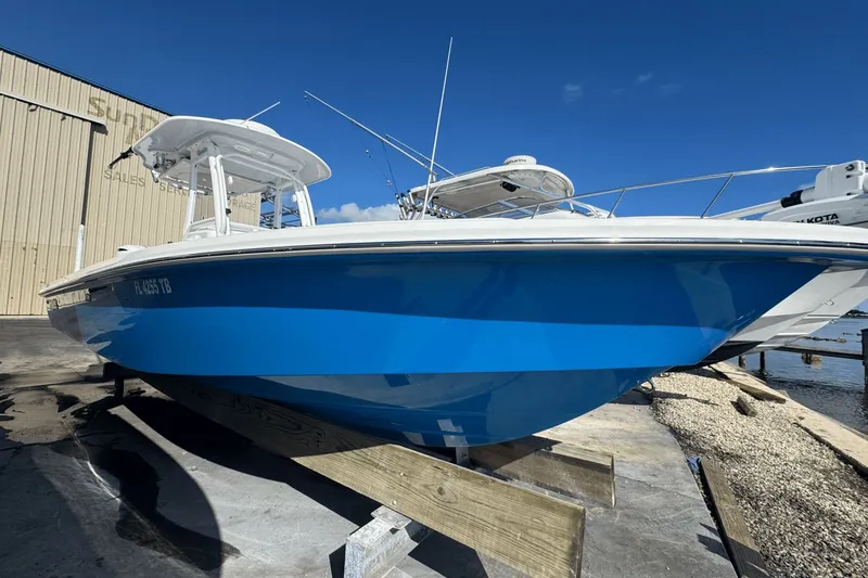 Slide: The Image of 2021 Everglades 243 CC boat in vibrant blue, docked under clear skies. - 4