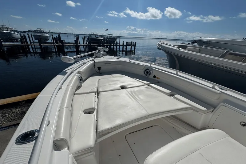 Slide: The Image of 2021 Everglades 243 CC boat with white seating, docked by the water under a clear sky. - 6