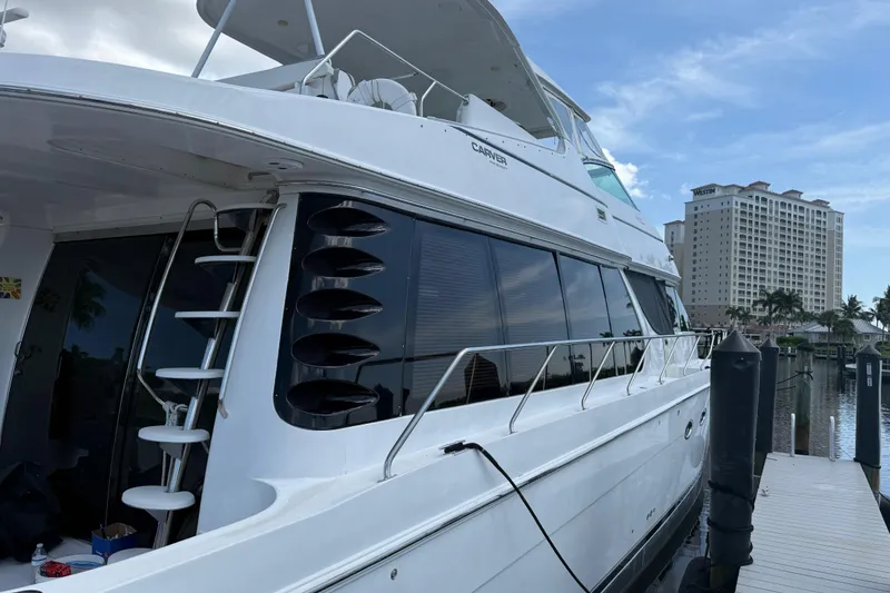 Slide: The Image of 2002 Carver 570 Voyager Pilothouse yacht docked at marina with cityscape background. - 3