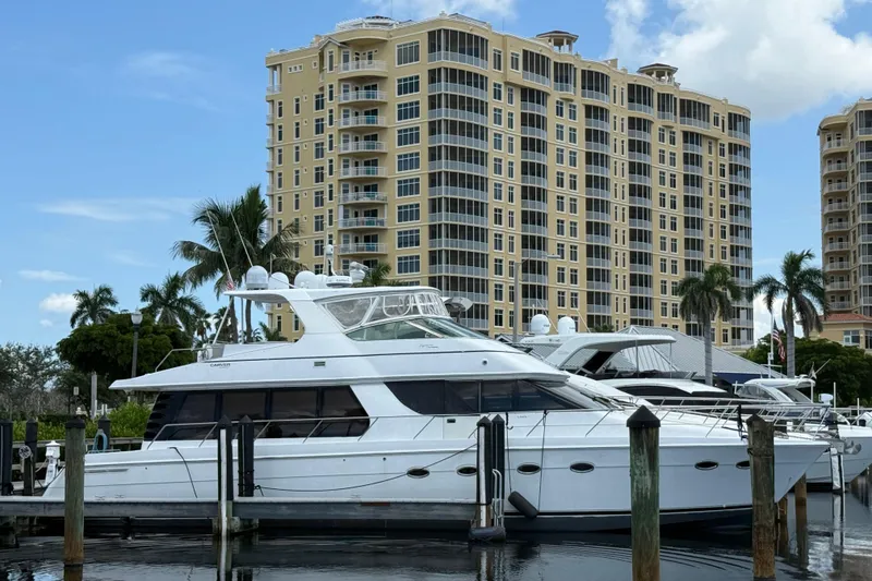 The Image of 2002 Carver 570 Voyager Pilothouse yacht docked near luxury waterfront buildings. - 0