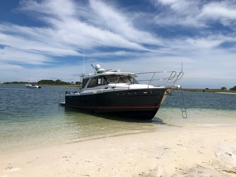 Slide: The Image of 2025 Cutwater C-32 Sedan boat on sandy beach with clear blue sky. - 3
