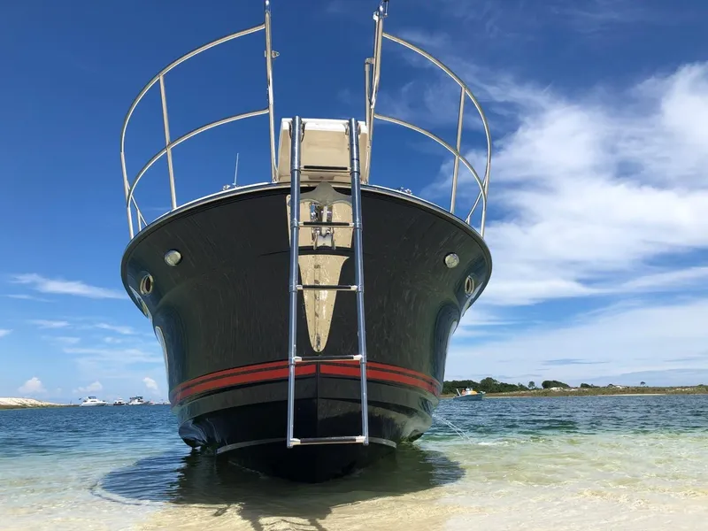 Slide: The Image of 2025 Cutwater C-32 Sedan boat on sandy shore under blue sky. - 5