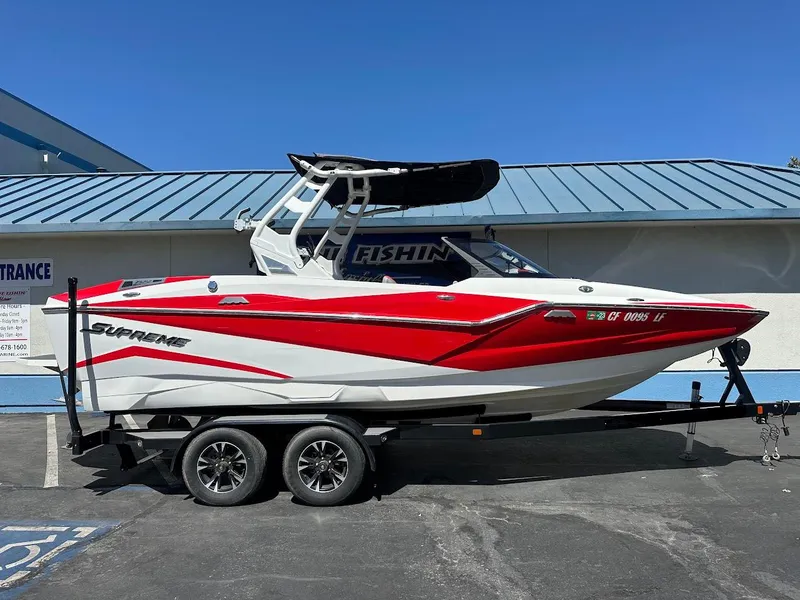Slide: The Image of 2021 Supreme ZS212 boat in red and white on a trailer, parked outdoors. - 1