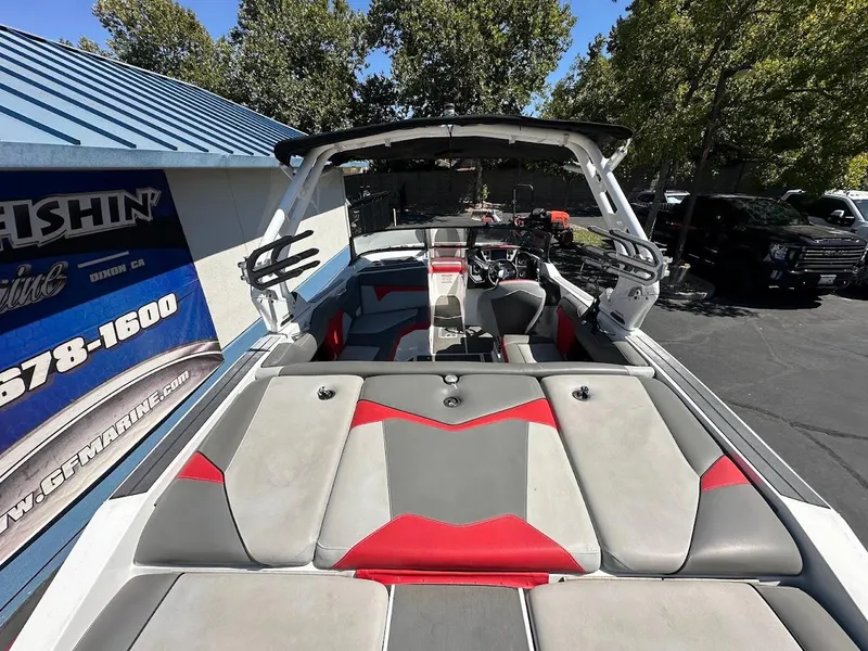 Slide: The Image of 2021 Supreme ZS212 boat with red and gray seating, parked near a blue-roofed building. - 12
