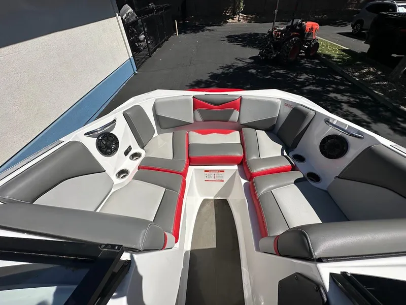Slide: The Image of 2021 Supreme ZS212 boat interior with gray and red seating, speakers, and cup holders. - 24