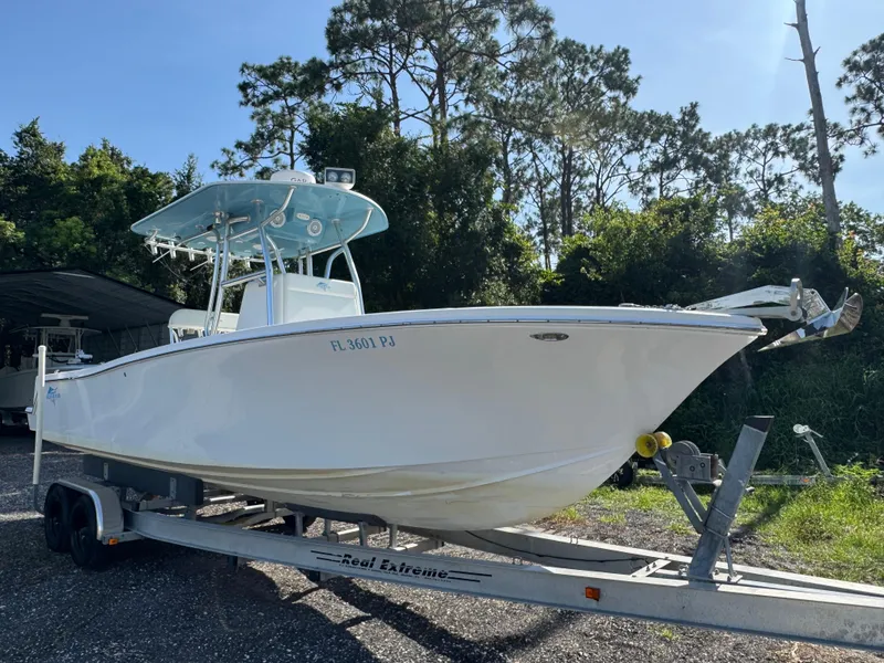 The Image of 2012 Ocean Runner 290i boat on trailer, surrounded by trees. - 1