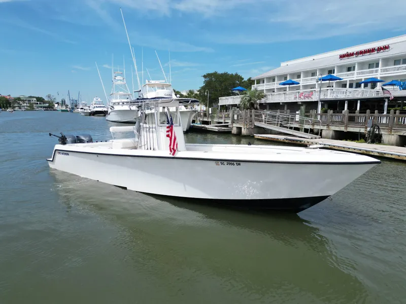 The Image of 2009 Contender 35 ST boat docked near a waterfront inn, under a clear blue sky. - 0