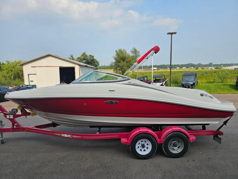 Slide: The Image of 2007 Sea Ray 210 Select boat on a trailer, red and white design, parked outdoors. - 3