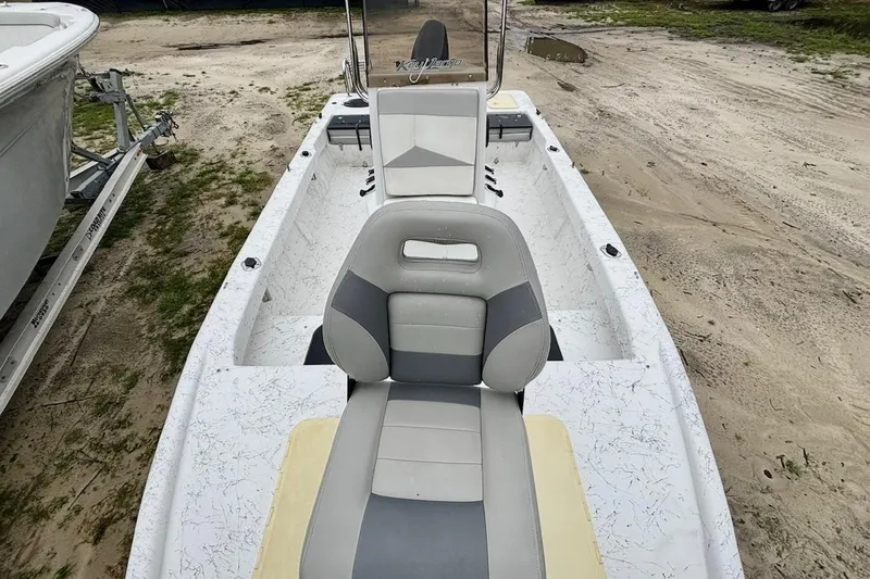 Slide: The Image of 2019 Key Largo 206 Bay boat interior with seating and console, parked on sandy ground. - 6