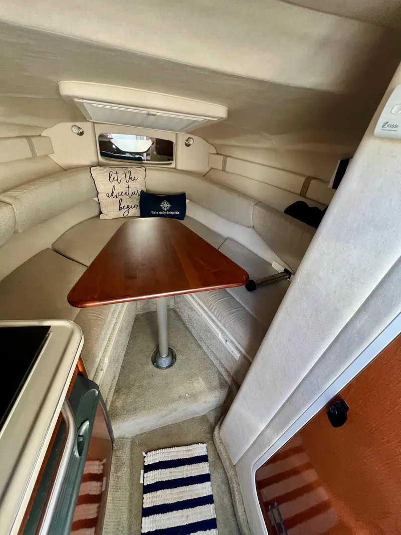 Slide: The Image of 2009 Sea Ray 240 Sundancer cabin interior with cozy seating and wooden table. - 10