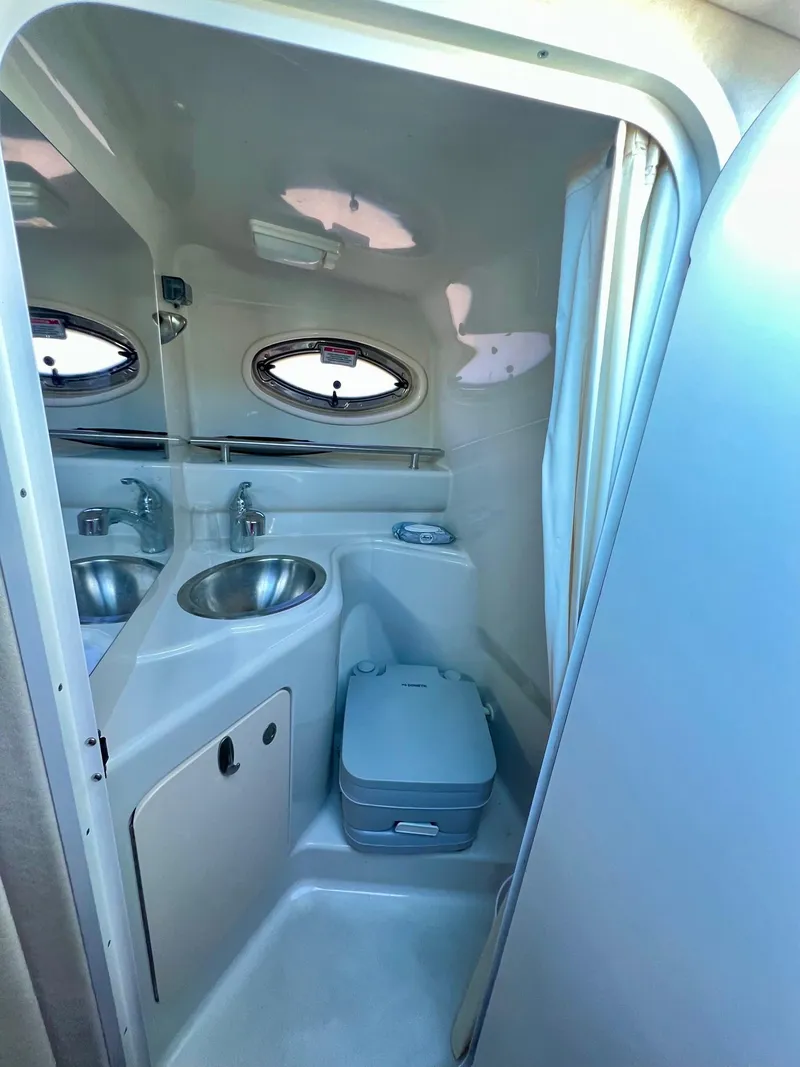 Slide: The Image of 2009 Sea Ray 240 Sundancer bathroom with sink, toilet, and porthole window. - 15