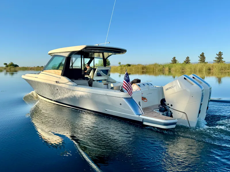 The Image of 2024 Chris-Craft Calypso 32 cruising on a serene lake with clear blue skies. - 0