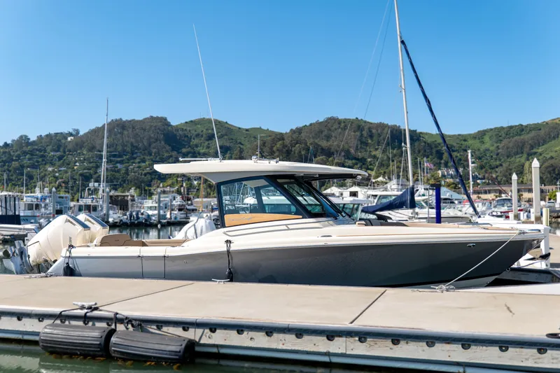 Slide: The Image of 2024 Chris-Craft Calypso 32 docked at a marina with scenic hillside backdrop. - 34