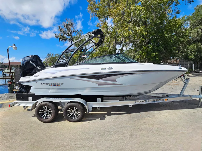 Slide: The Image of 2026 Monterey M-205 boat on trailer, parked outdoors under a clear blue sky. - 2