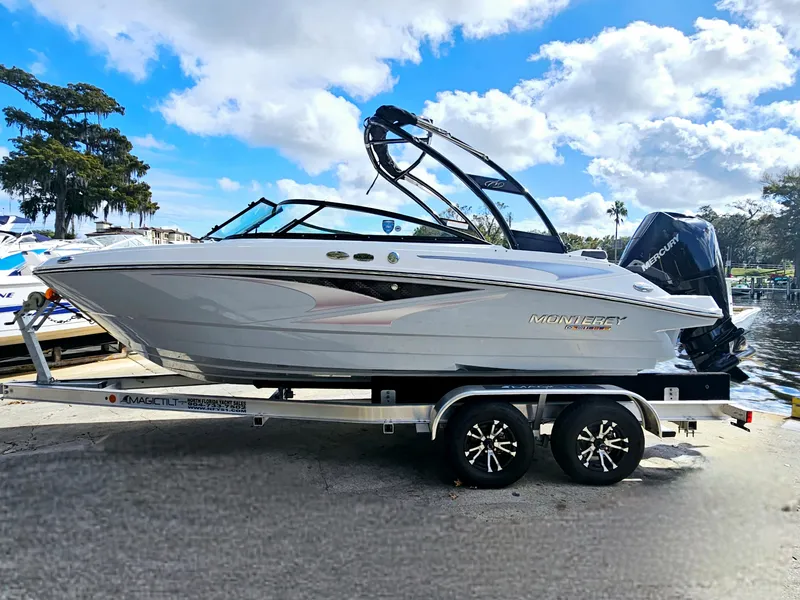 Slide: The Image of 2026 Monterey M-205 boat on trailer, parked by a scenic waterfront under a partly cloudy sky. - 9