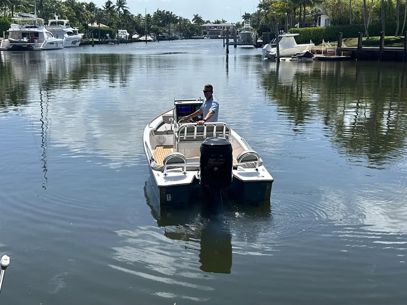 Slide: The Image of 2024 Dragonfly 21 Spanish Wells boat navigating a calm canal with palm trees. - 4