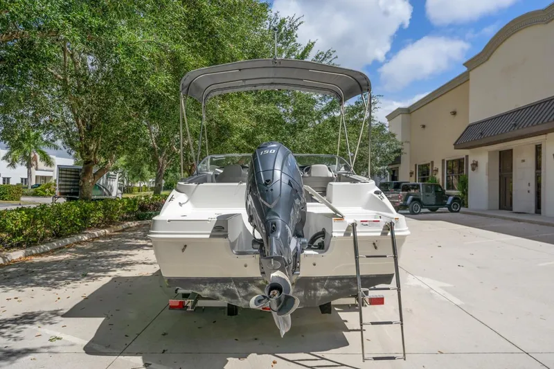 Slide: The Image of 2025 Hurricane SunDeck 217 OB boat with outboard motor, parked outdoors. - 16