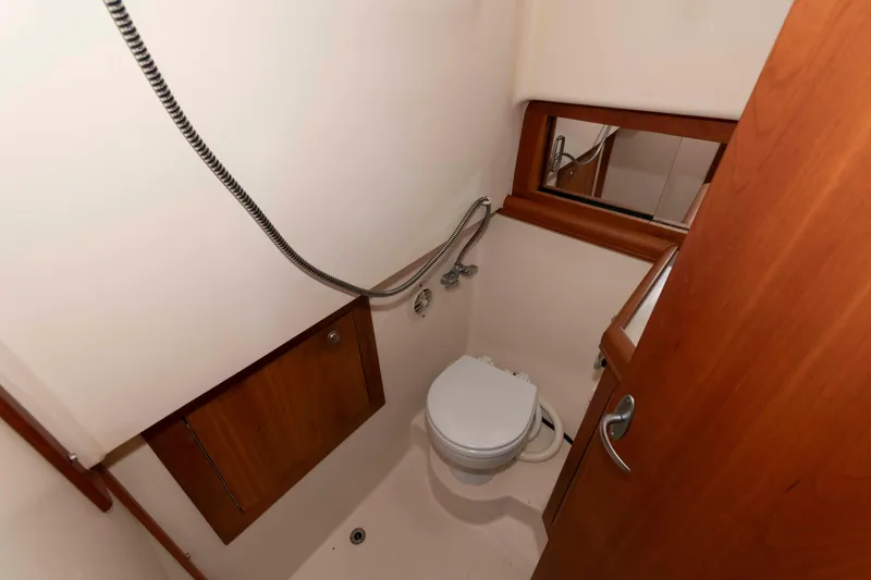 Slide: The Image of 2004 Mainship 34 Pilot Rum Runner II bathroom with toilet and showerhead. - 10