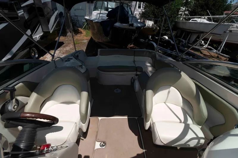 Slide: The Image of 2006 Sea Ray 240 Sundeck interior with seating and steering wheel, parked among other boats. - 11