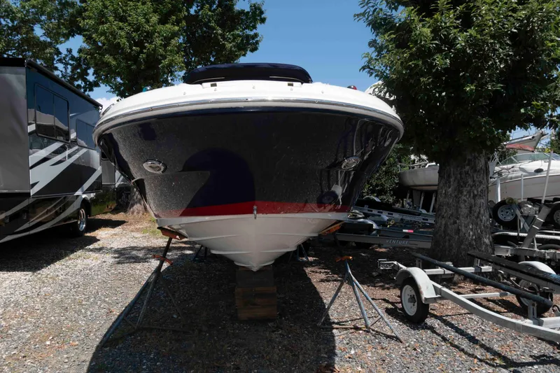 Slide: The Image of 2006 Sea Ray 240 Sundeck boat on stands, surrounded by trees and trailers. - 2