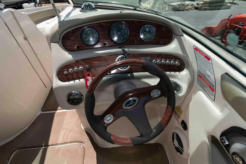 Slide: The Image of 2006 Sea Ray 240 Sundeck dashboard with wood accents and steering wheel. - 6