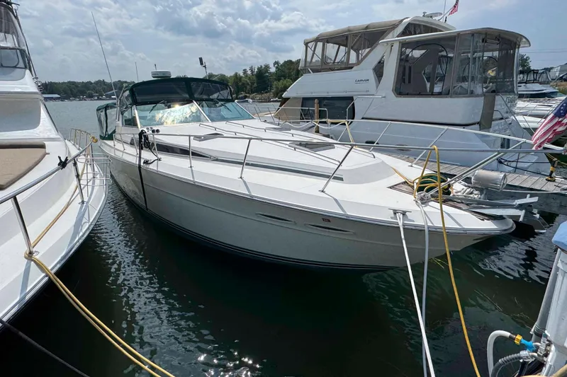 The Image of 1986 Sea Ray 390 Express Cruiser docked at marina, surrounded by other boats. - 0