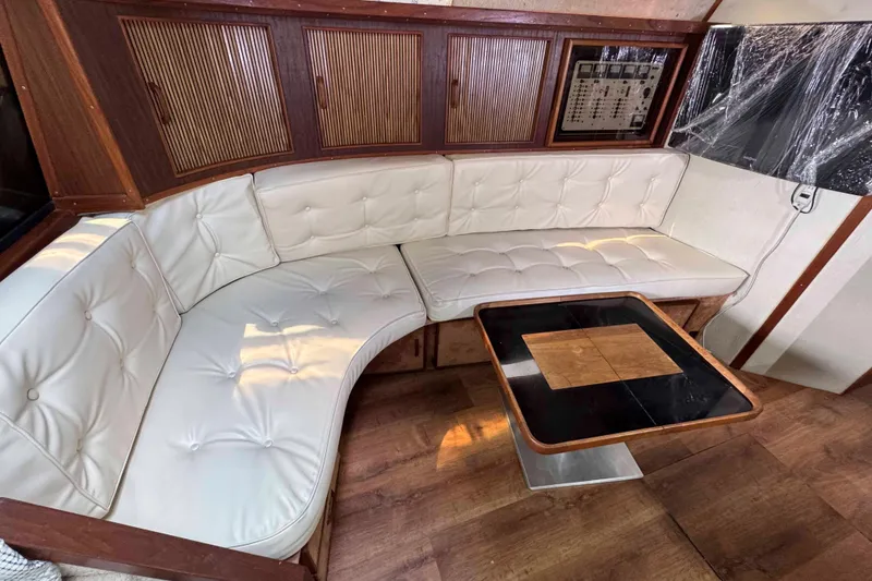 Slide: The Image of 1986 Sea Ray 390 Express Cruiser interior with white leather seating and wooden table. - 11