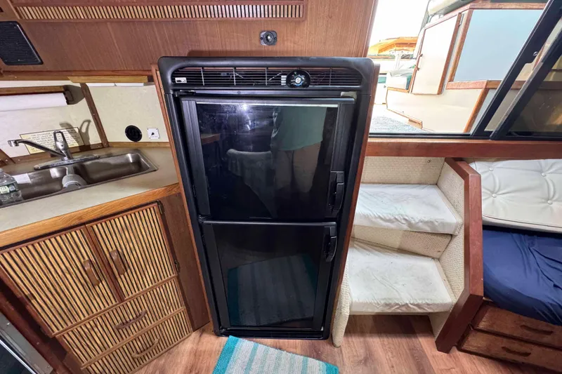 Slide: The Image of 1986 Sea Ray 390 Express Cruiser interior with kitchenette, fridge, and stairs. - 12