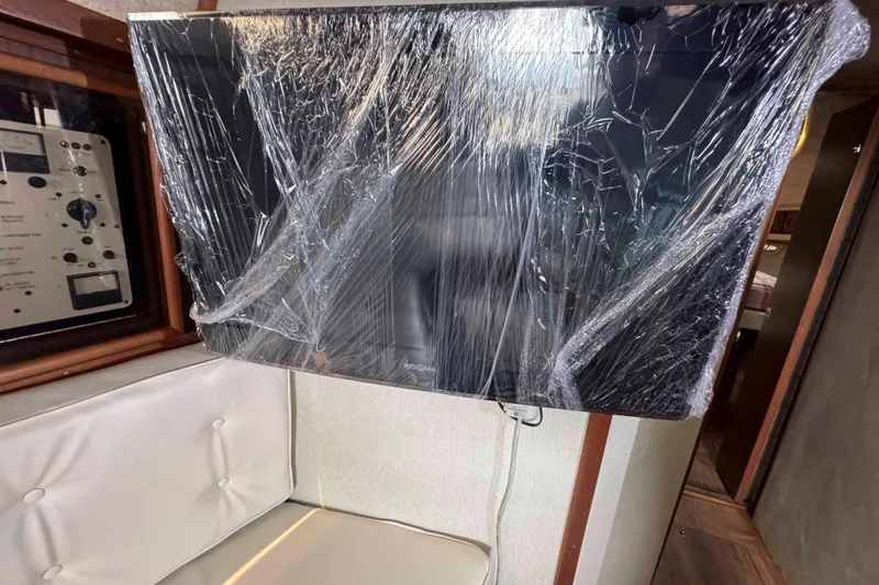 Slide: The Image of Plastic-wrapped TV inside 1986 Sea Ray 390 Express Cruiser cabin. - 13