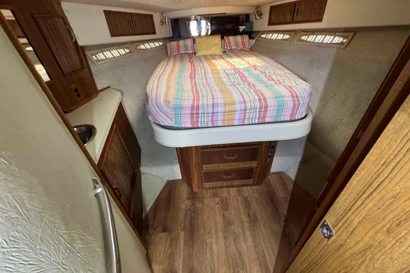 Slide: The Image of 1986 Sea Ray 390 Express Cruiser cabin with bed, wood accents, and compact design. - 14