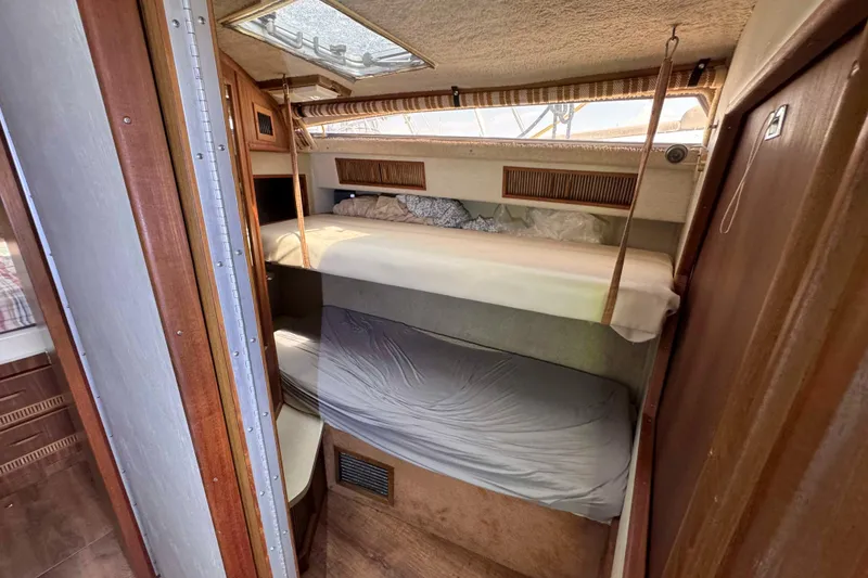 Slide: The Image of 1986 Sea Ray 390 Express Cruiser cabin with bunk beds and wooden interior. - 17