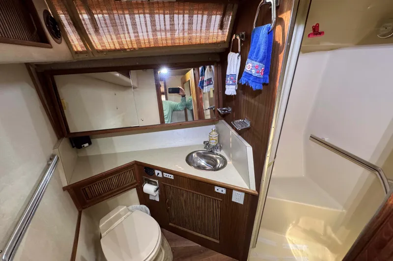 Slide: The Image of 1986 Sea Ray 390 Express Cruiser bathroom with sink, mirror, and shower area. - 18