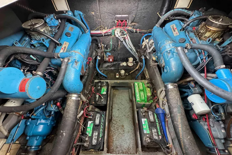 Slide: The Image of Engine room of 1986 Sea Ray 390 Express Cruiser with twin blue engines and batteries. - 19
