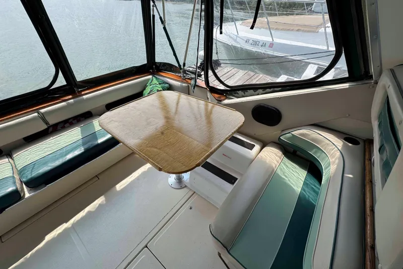 Slide: The Image of Interior of 1986 Sea Ray 390 Express Cruiser with seating and table, docked by water. - 7