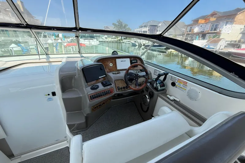 Slide: The Image of 2009 Rinker 340 Express Cruiser cockpit with steering wheel, navigation system, and waterfront view. - 11