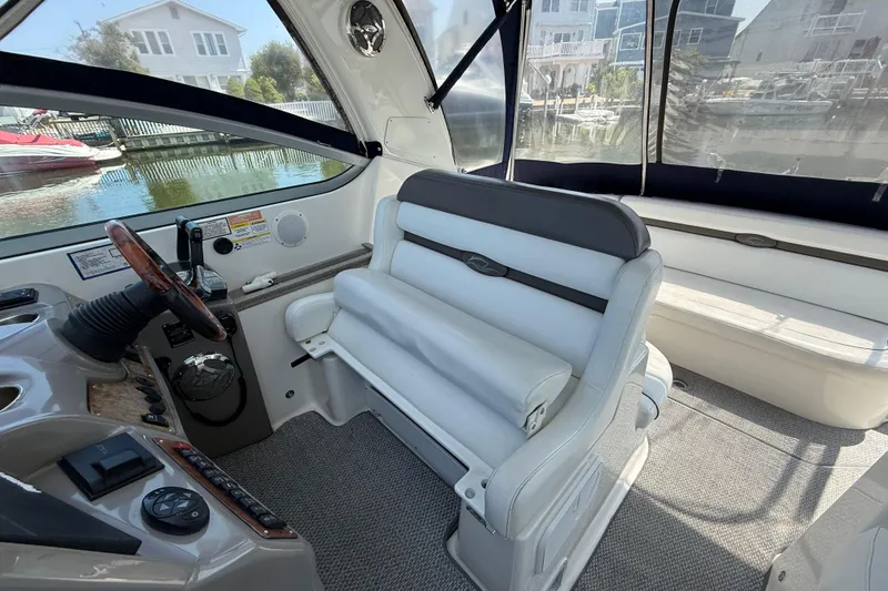 Slide: The Image of 2009 Rinker 340 Express Cruiser interior with helm and seating, docked near waterfront homes. - 13