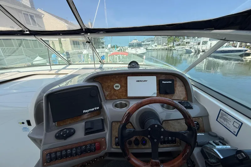 Slide: The Image of 2009 Rinker 340 Express Cruiser helm with Raymarine navigation, docked in a marina. - 15