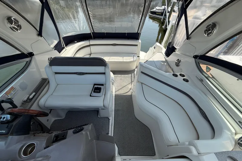 Slide: The Image of 2009 Rinker 340 Express Cruiser interior with white seating and helm, docked by water. - 16