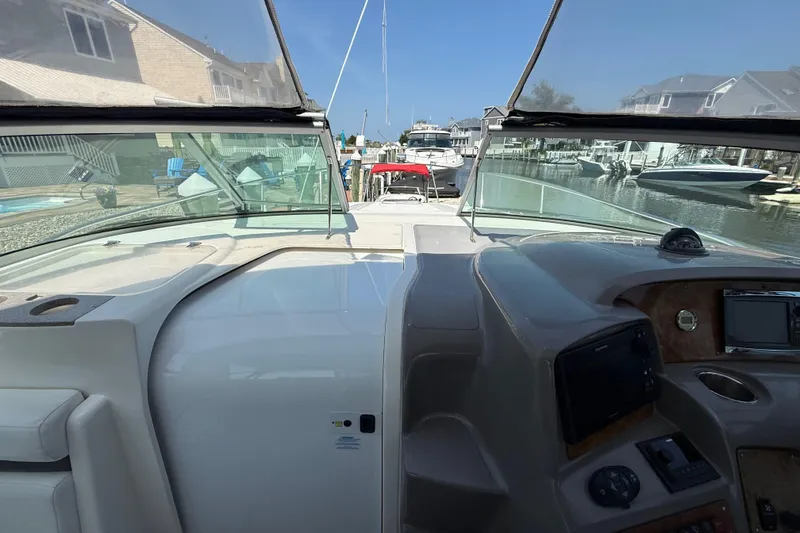 Slide: The Image of 2009 Rinker 340 Express Cruiser cockpit view, docked in a marina with surrounding boats. - 19