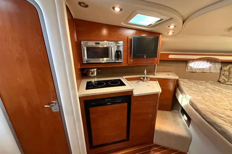 Slide: The Image of 2009 Rinker 340 Express Cruiser interior with kitchenette and cozy sleeping area. - 24