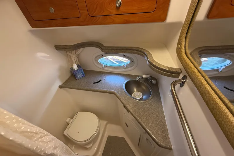 Slide: The Image of 2009 Rinker 340 Express Cruiser bathroom with sink, toilet, and porthole window. - 29