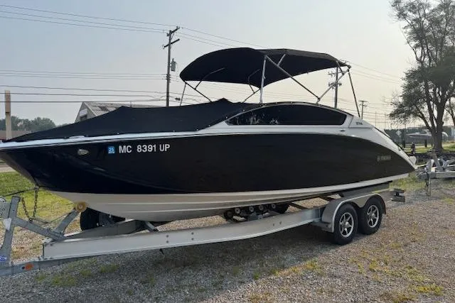 Slide: The Image of 2021 Yamaha Boats 275 SE on trailer, black hull, parked outdoors. - 2