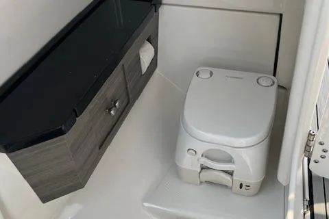 Slide: The Image of 2021 Yamaha Boats 275 SE interior with compact marine toilet and storage cabinet. - 20