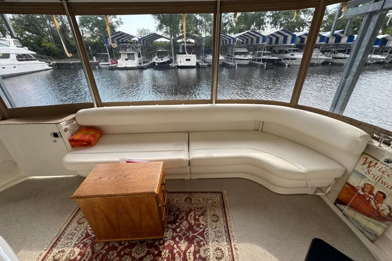 Slide: The Image of 2004 Sea Ray 390 Motor Yacht interior with white seating, wooden table, and marina view. - 10