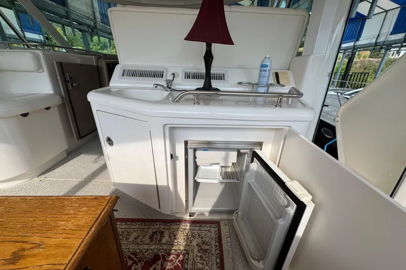 Slide: The Image of 2004 Sea Ray 390 Motor Yacht interior with open mini fridge and sink area. - 13