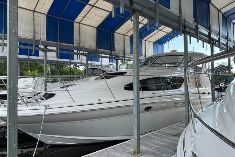 Slide: The Image of 2004 Sea Ray 390 Motor Yacht docked under a blue and white canopy. - 2