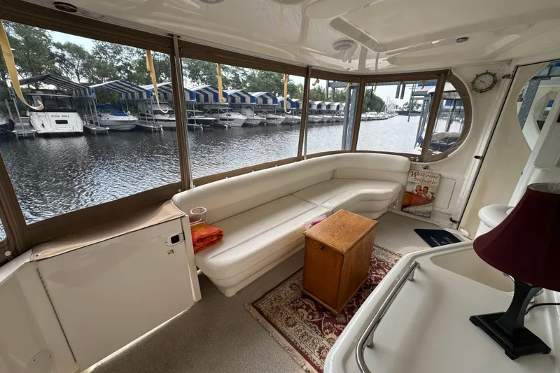 Slide: The Image of 2004 Sea Ray 390 Motor Yacht interior with white seating, wooden table, and marina view. - 9