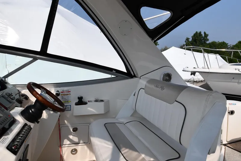 Slide: The Image of 2011 Sea Ray 310 Sundancer cockpit with white seating and wooden steering wheel. - 17